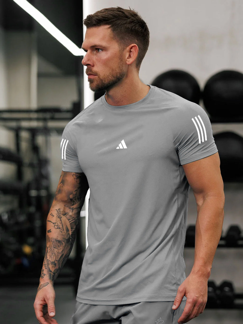 URBAN WOLFS men's grey dry-fit gym tee on athletic model with short sleeves and white logo in gym