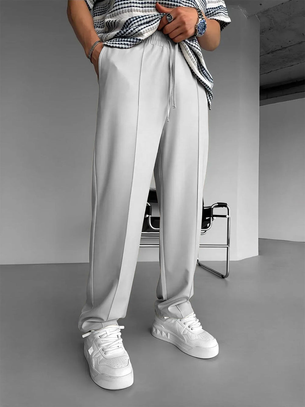 Model wearing URBAN WOLFS men's light grey baggy joggers with drawstring waist and white sneakers