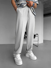 Model wearing URBAN WOLFS men's light grey baggy joggers with drawstring waist and white sneakers