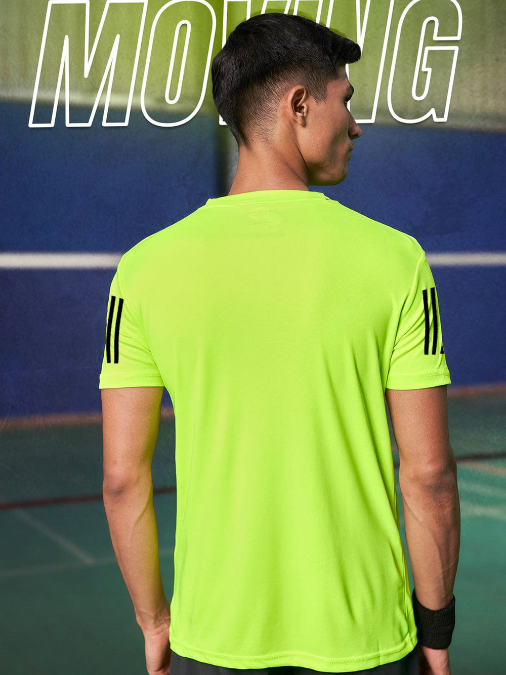 Back view of male model wearing men's lime green dri-fit t-shirt with black sleeve stripes on sports court