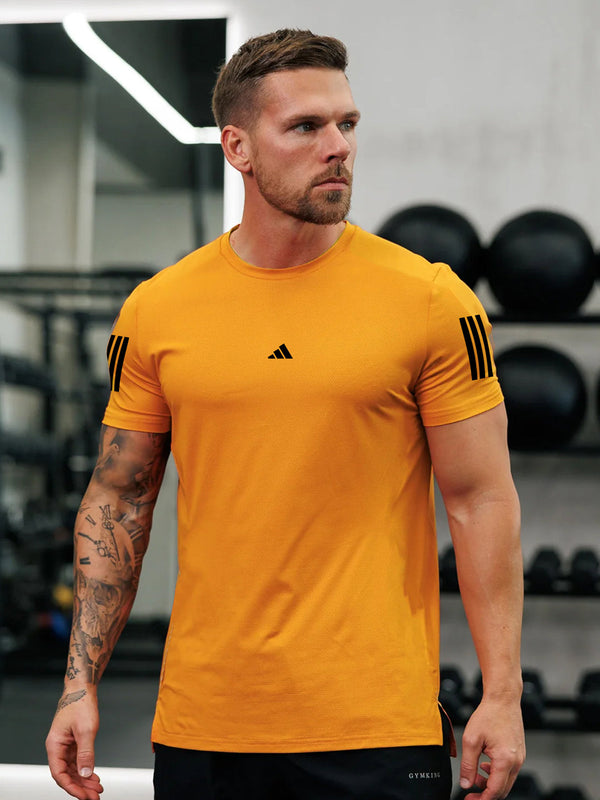 URBAN WOLFS men's neon orange dry-fit t-shirt on muscular male model in gym showing slim fit and short sleeves