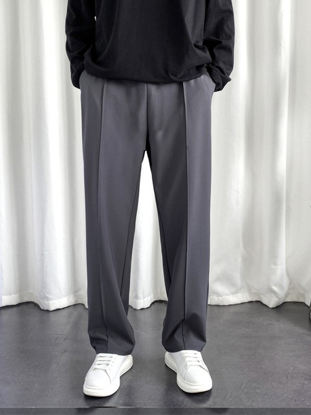 Front view of men's charcoal baggy joggers styled with a black long sleeve top and white sneakers