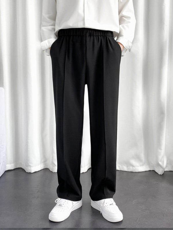 Model wearing URBAN WOLFS men's black baggy joggers with elastic waist straight wide legs and white sneakers